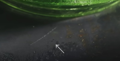 Alpha particle track, probably background, next to uranium glass in an isopropyl alcohol cloud chamber in Adam Ragusea's kitchen