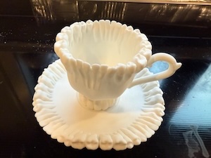 A 3-d printed cup and saucer, edged with human teeth.